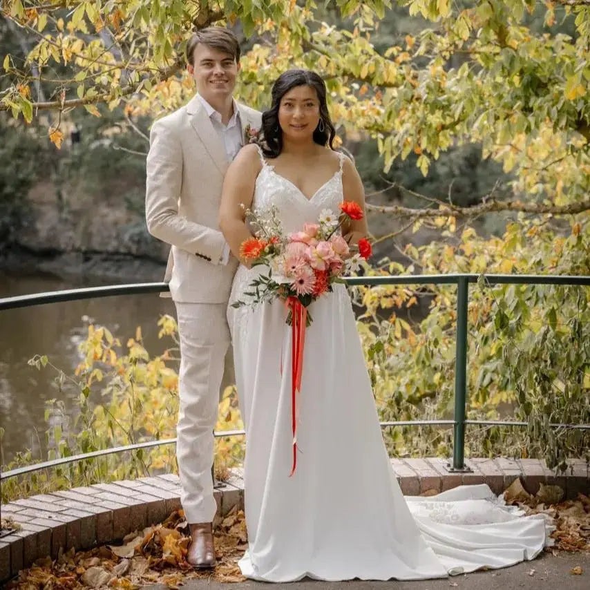 Bride in Harlow Wedding Dress with V-neckline and lace appliqué standing with groom