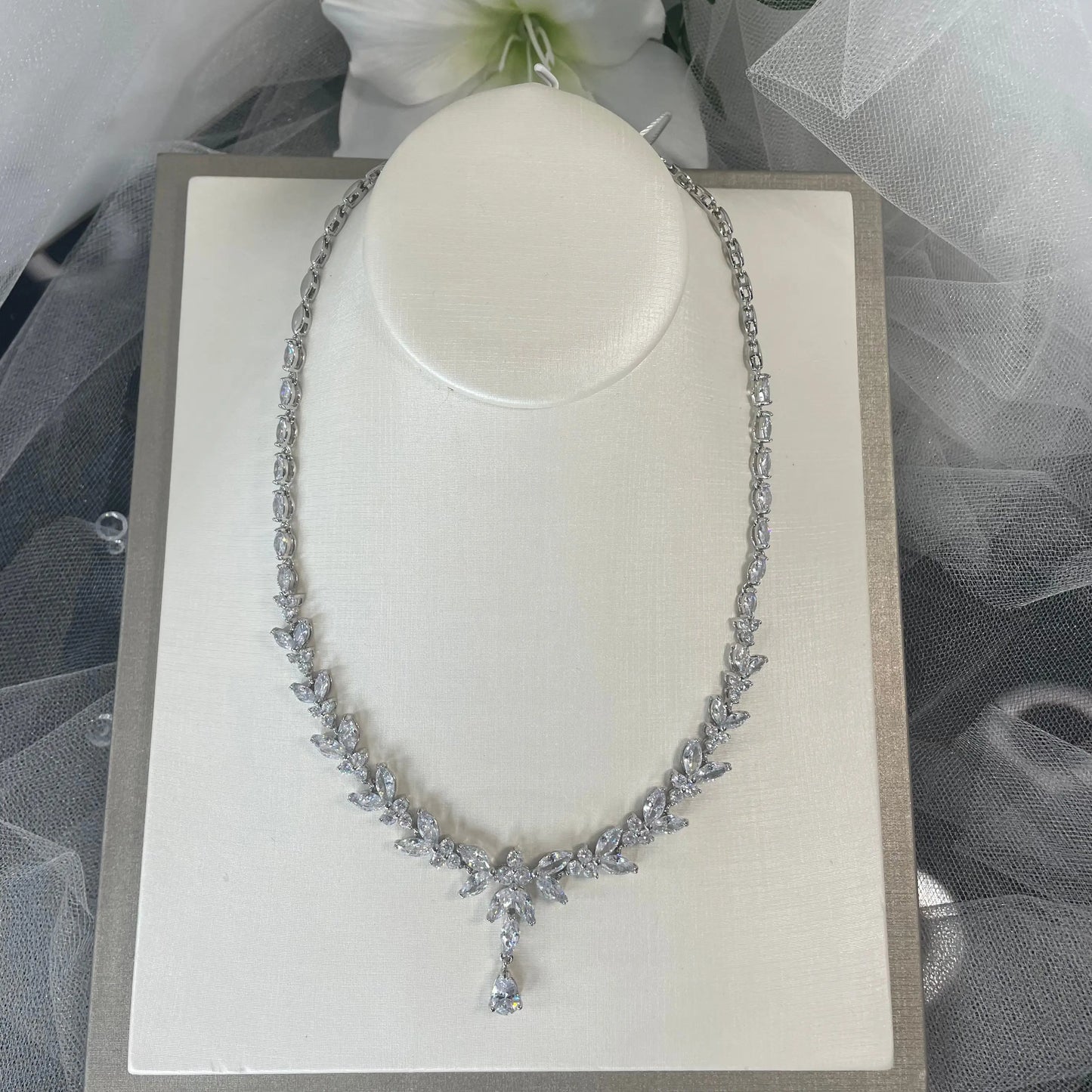 Silver Necklace: An elegant silver necklace with a leaf and flower design adorned with clear cubic zirconia.