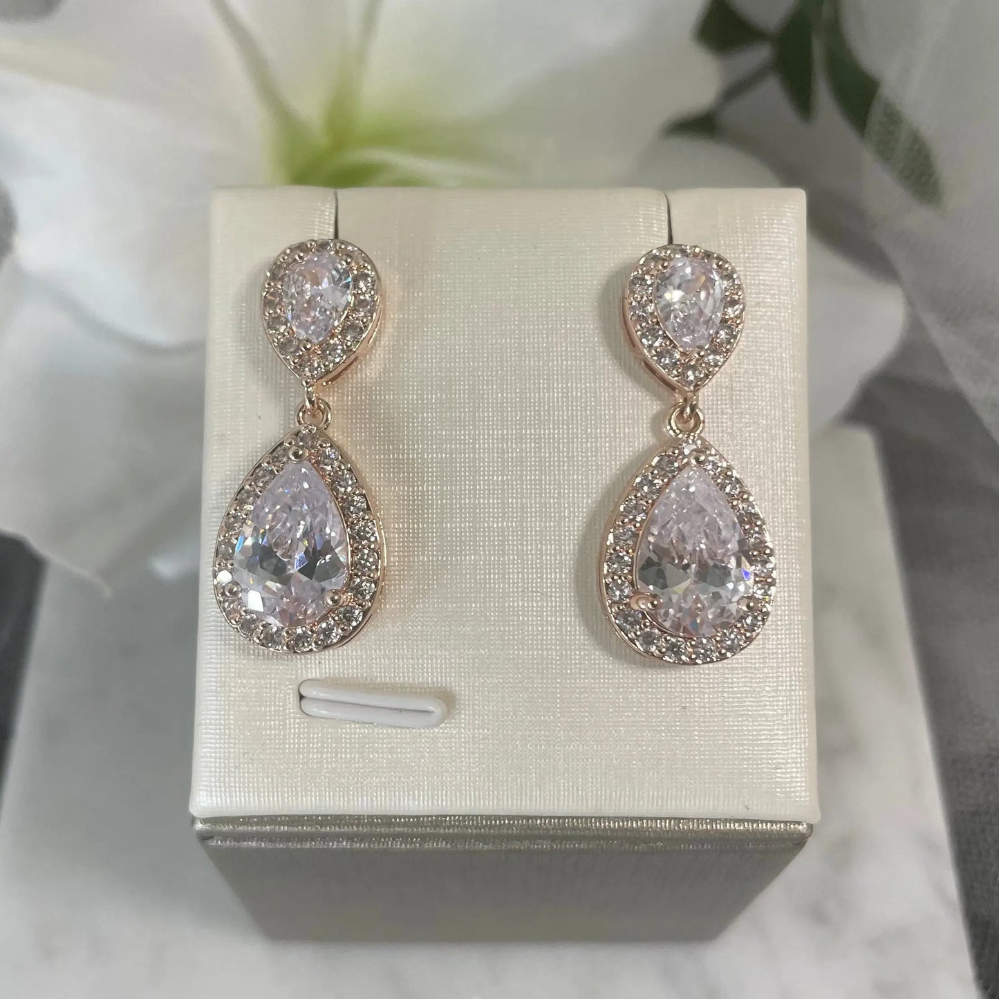 Leona Earrings (Rose Gold): Elegant rose gold earrings with a large CZ stone surrounded by smaller CZs, offering a sophisticated drop design.