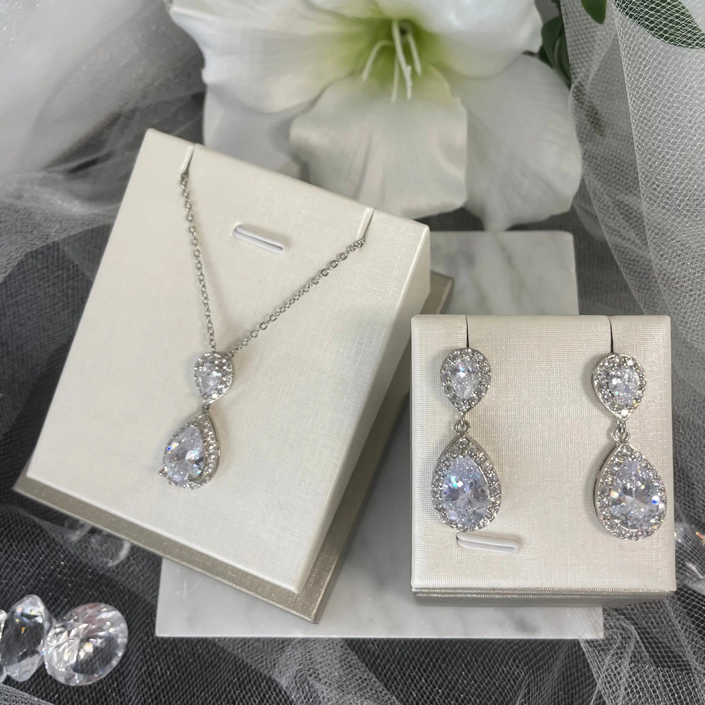 Leona Necklace & Earring Set (Silver): A stunning silver necklace and earring set featuring large CZ stones surrounded by smaller CZs, perfect for special occasions.