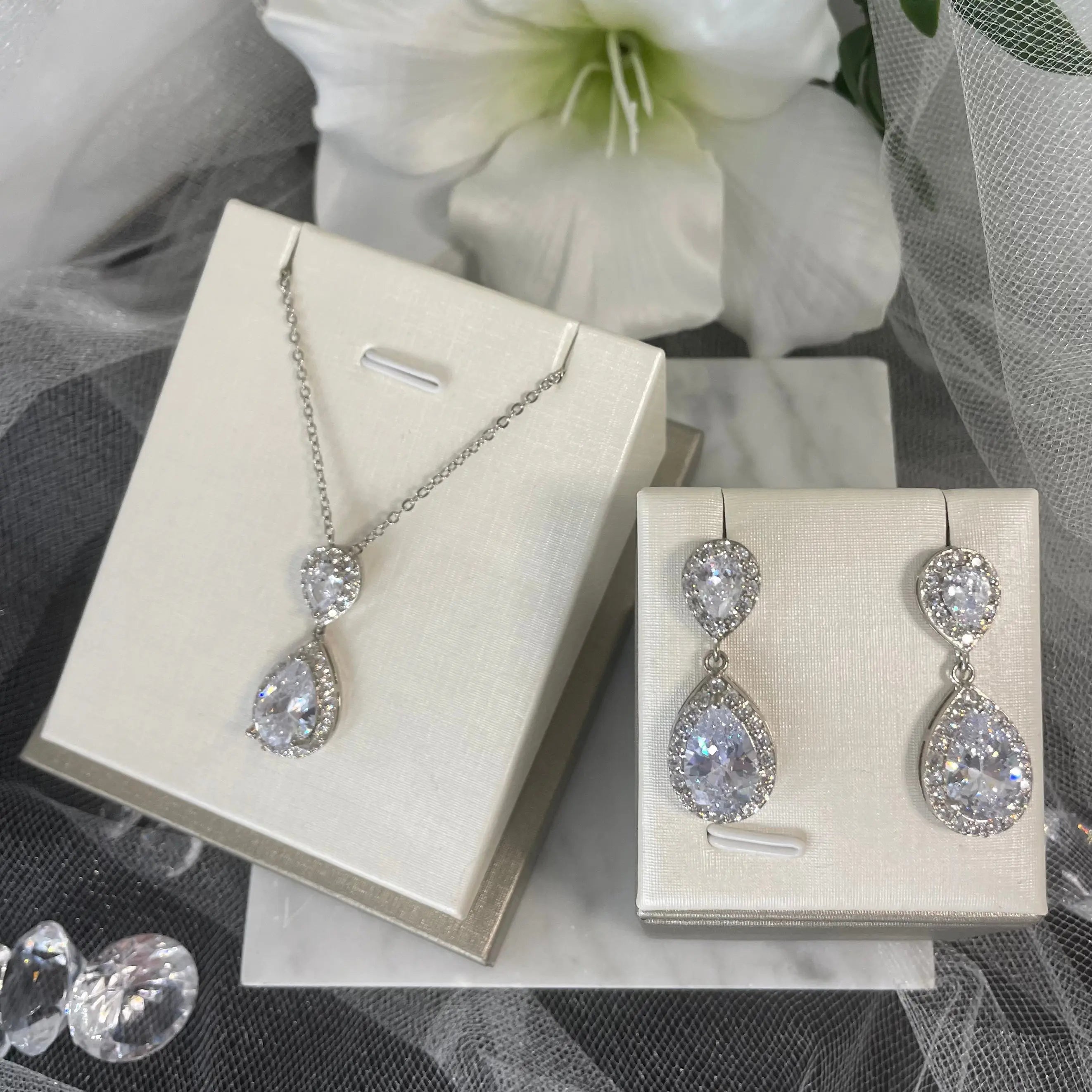 Leona Necklace & Earring Set (Silver): A stunning silver necklace and earring set featuring large CZ stones surrounded by smaller CZs, perfect for special occasions.