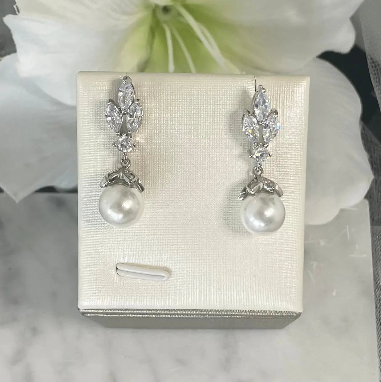 Levin crystal pearl earrings with a three-leaf design and central crystal, accented by a delicately held pearl, perfect for enhancing any bridal ensemble.