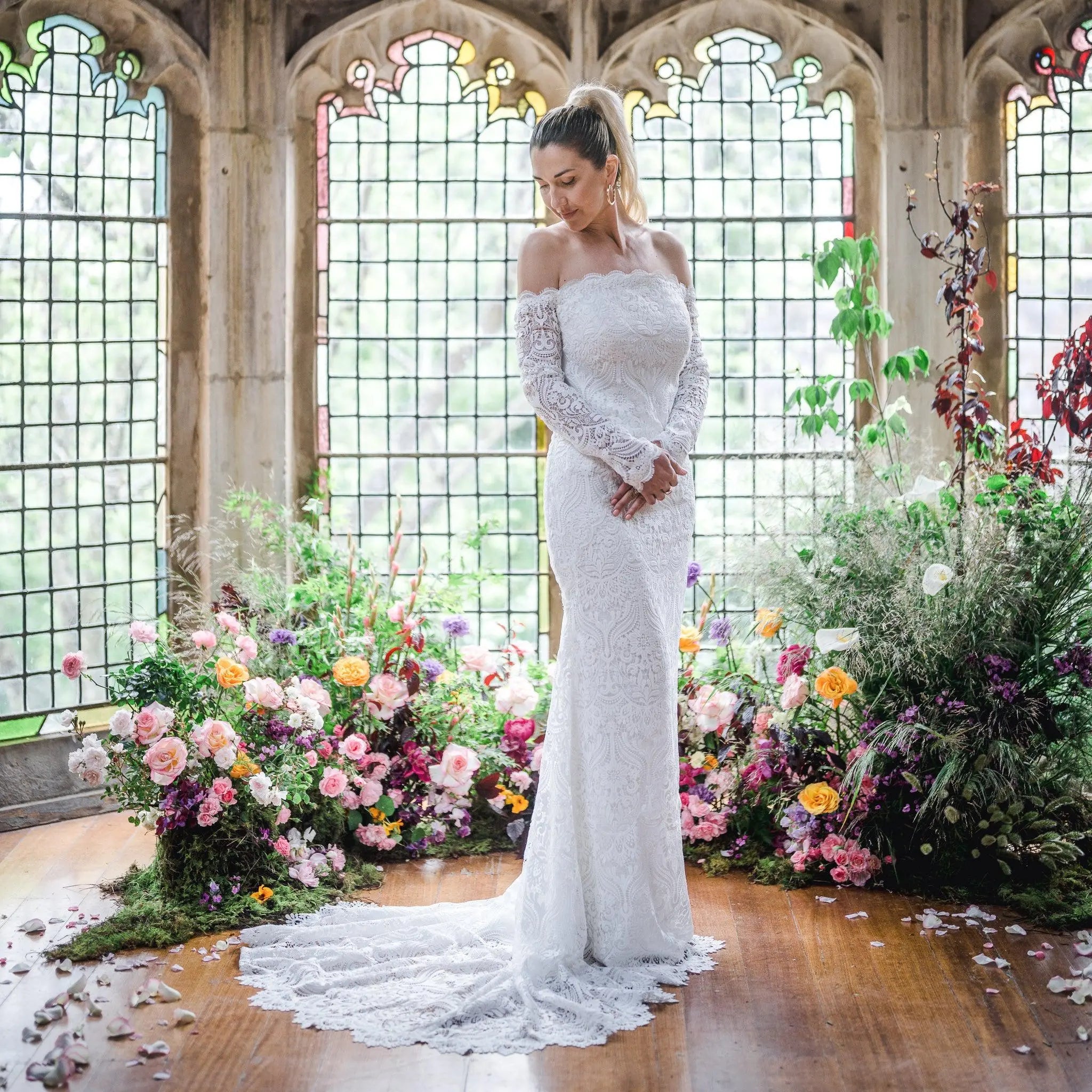 Stunning bride in the Celaya wedding dress featuring off-the-shoulder sleeves, scalloped trim, and a gracefully trailing chapel train.