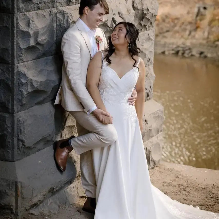 Bride in Harlow Wedding Dress with V-neckline and lace appliqué standing with groom