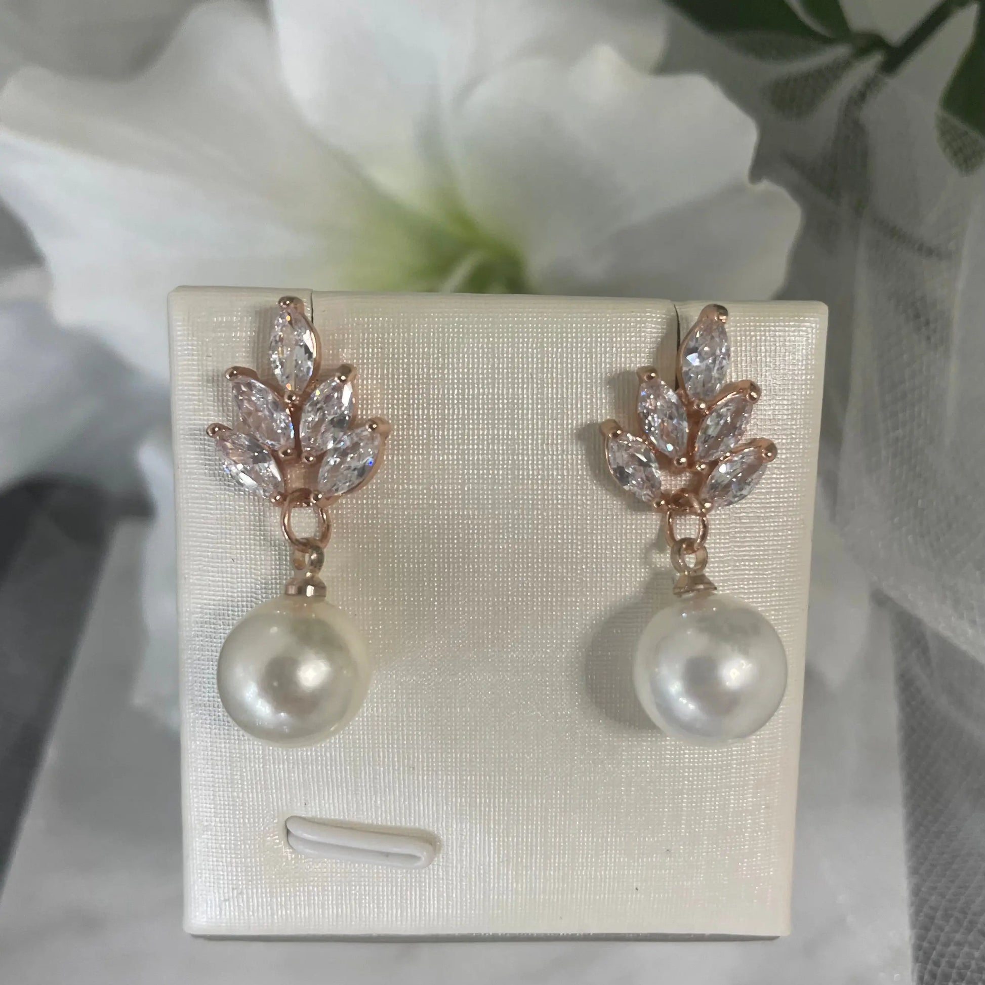 Earrings in Rose Gold: Elegant rose gold earrings with a leaf design and dangling teardrop pearls.