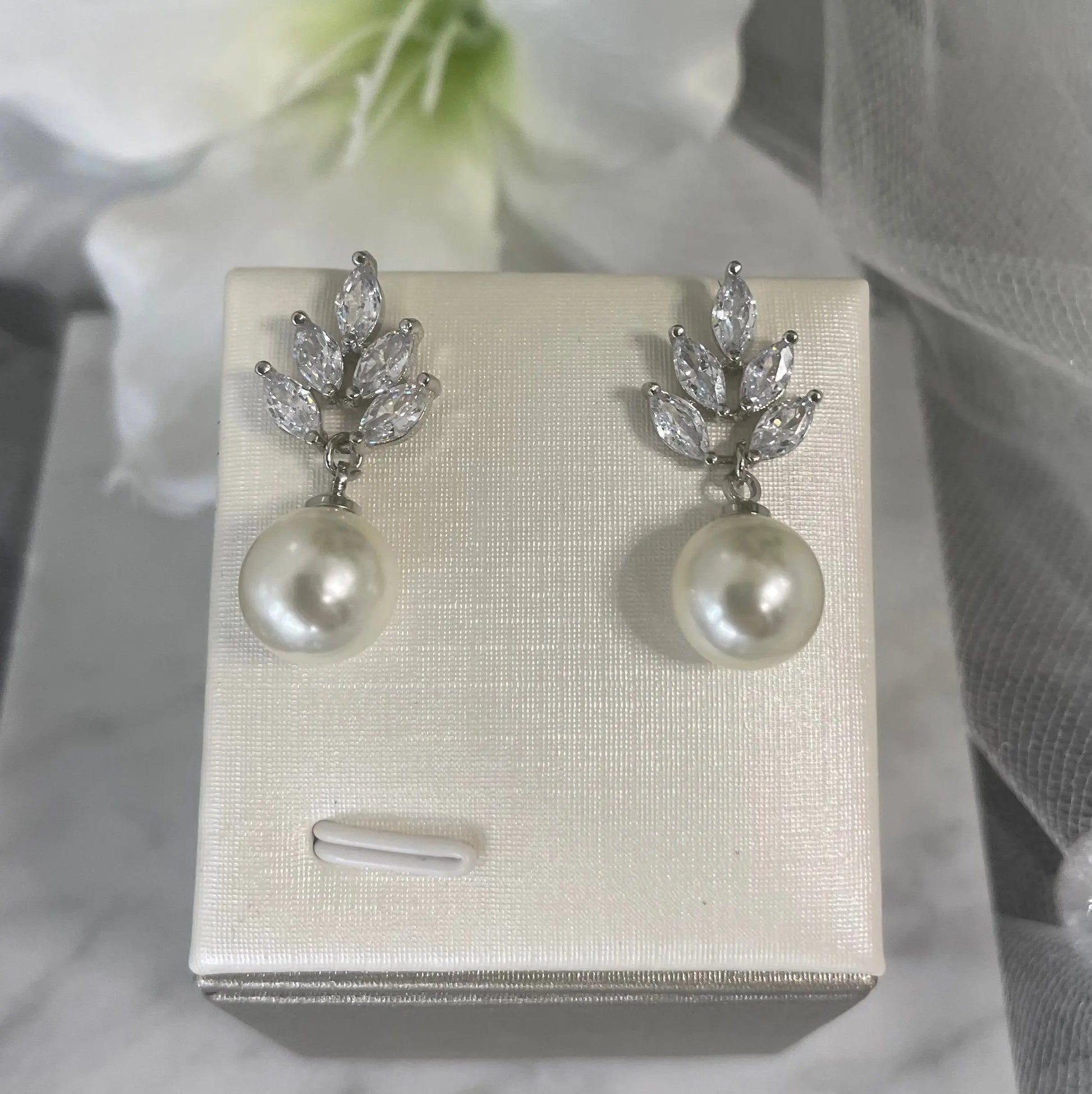 Earrings in Silver: Sophisticated silver earrings with a leaf design and dangling teardrop pearls.