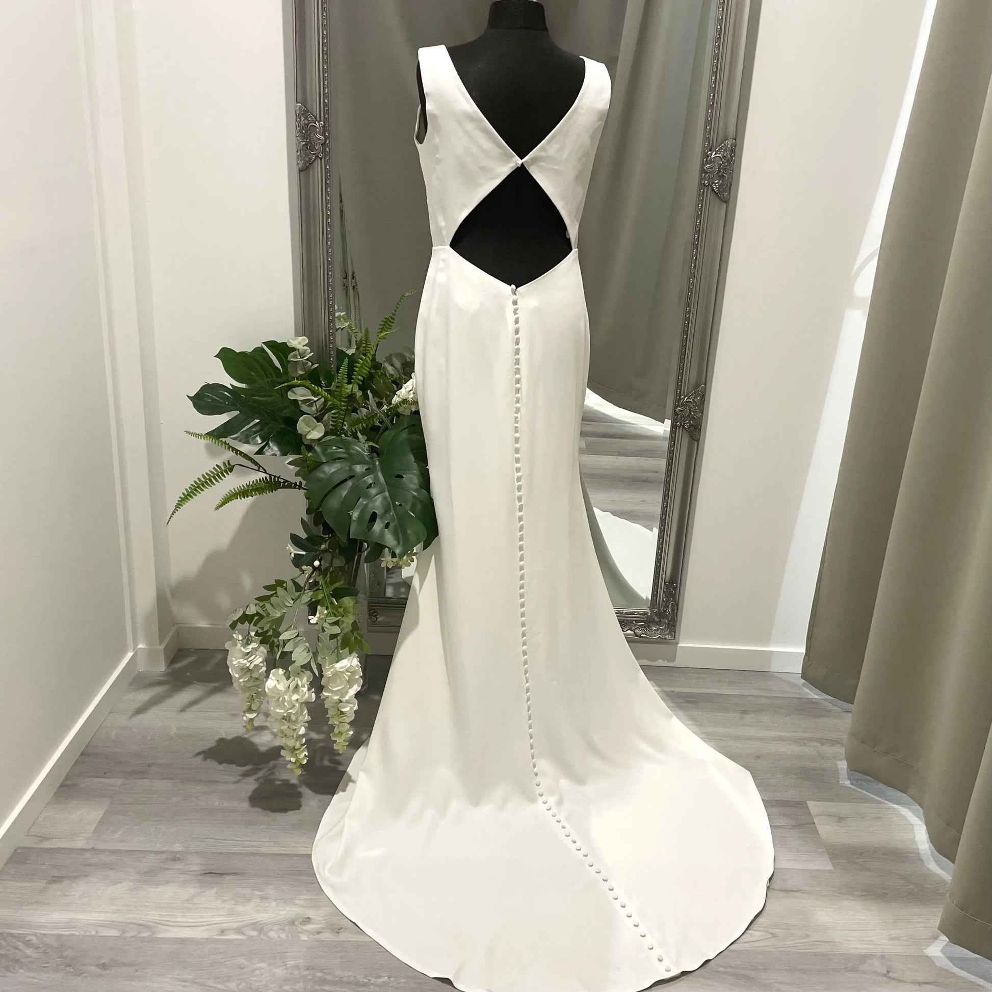 Back view of the Penny Wedding Gown showcasing the intricate diamond cutout at the waist, V-neckline, and buttons running down to the chapel train. This elegant and sophisticated detail adds a touch of glamour to the beautiful bridal dress.