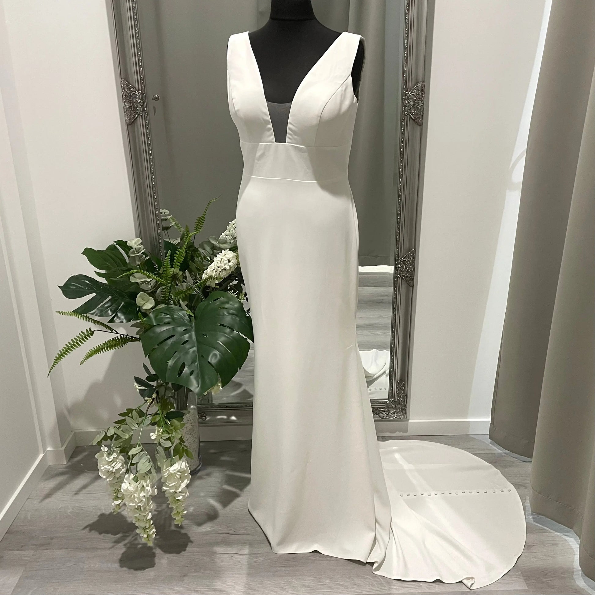 Front view of the Penny Wedding Gown featuring a strap V-neckline with illusion insert, delicate lace patterns, and a flattering fit that accentuates the bride's natural curves. Experience beautiful bridal elegance with this stunning gown.